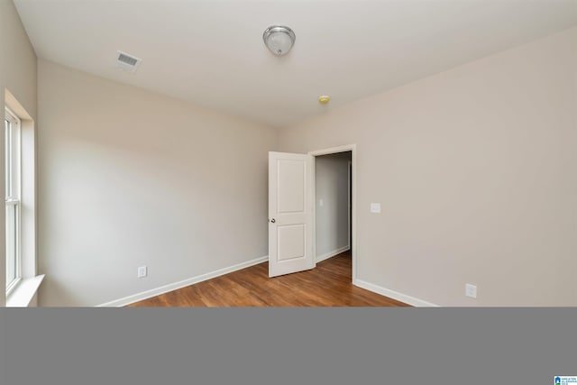 empty room featuring baseboards, visible vents, and wood finished floors