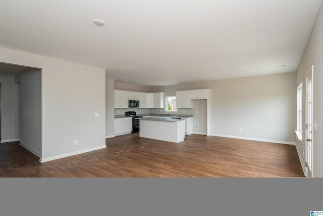 interior space featuring black appliances, white cabinets, dark wood-type flooring, and a center island