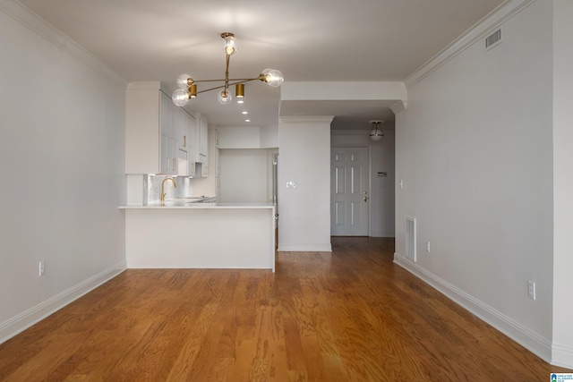 unfurnished living room with crown molding, wood-type flooring, and sink