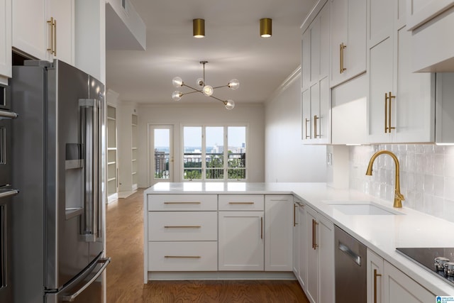 kitchen with appliances with stainless steel finishes, white cabinetry, sink, kitchen peninsula, and crown molding