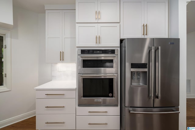 kitchen with appliances with stainless steel finishes, dark hardwood / wood-style floors, decorative backsplash, and white cabinets