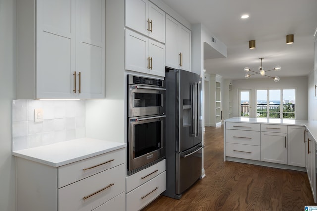 kitchen with tasteful backsplash, dark hardwood / wood-style flooring, kitchen peninsula, stainless steel appliances, and white cabinets