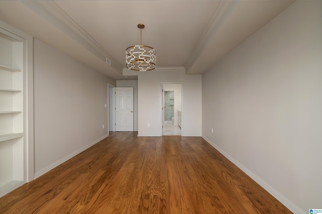 empty room featuring wood-type flooring, an inviting chandelier, and crown molding