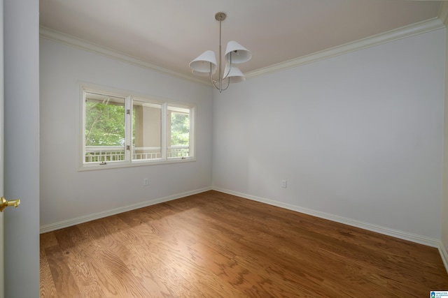 spare room featuring hardwood / wood-style floors, crown molding, and a notable chandelier