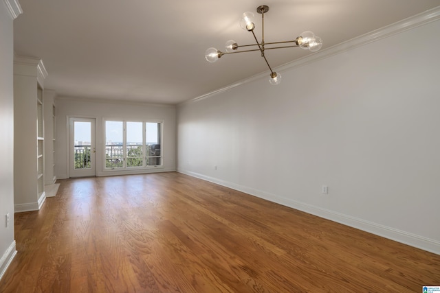 spare room featuring crown molding, hardwood / wood-style floors, and a notable chandelier