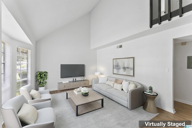 living room featuring high vaulted ceiling, electric panel, and light wood-type flooring