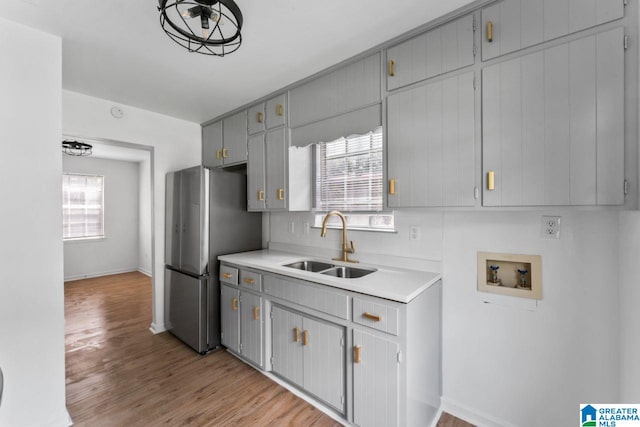 kitchen with gray cabinets, stainless steel refrigerator, sink, and light hardwood / wood-style floors