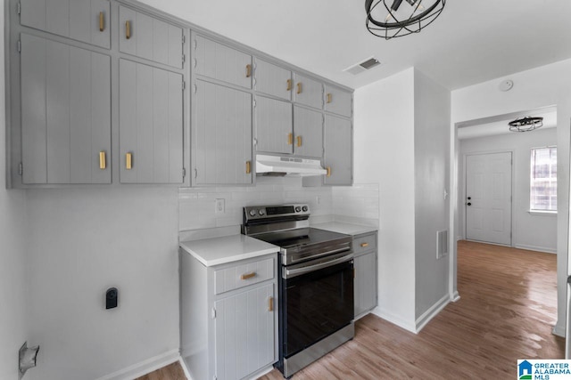 kitchen featuring gray cabinetry, decorative backsplash, light wood-type flooring, and electric stove