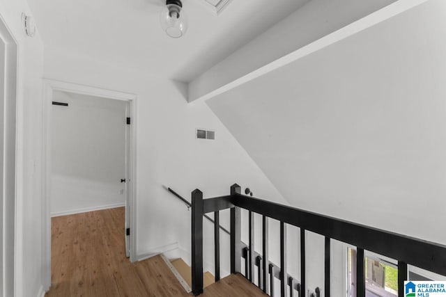 staircase featuring hardwood / wood-style floors and vaulted ceiling with beams