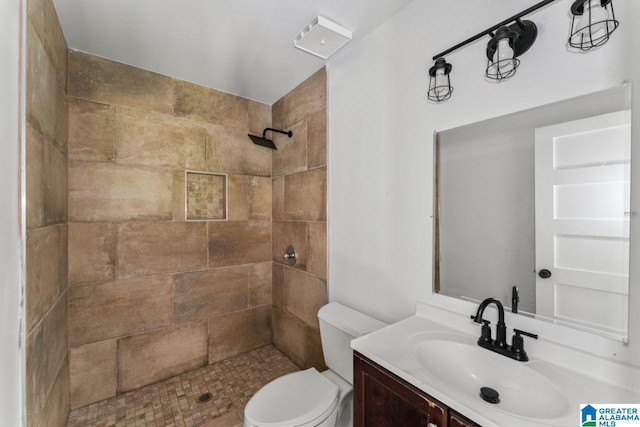 bathroom with vanity, tiled shower, and toilet