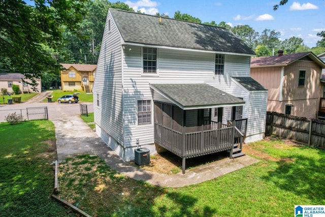 rear view of property with central AC and a lawn