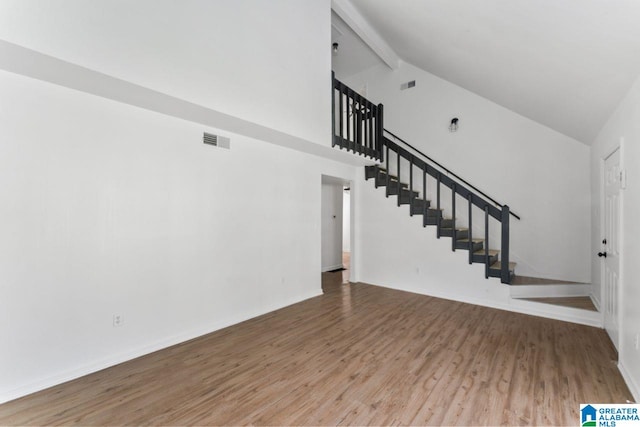 unfurnished living room featuring hardwood / wood-style flooring, beam ceiling, and high vaulted ceiling