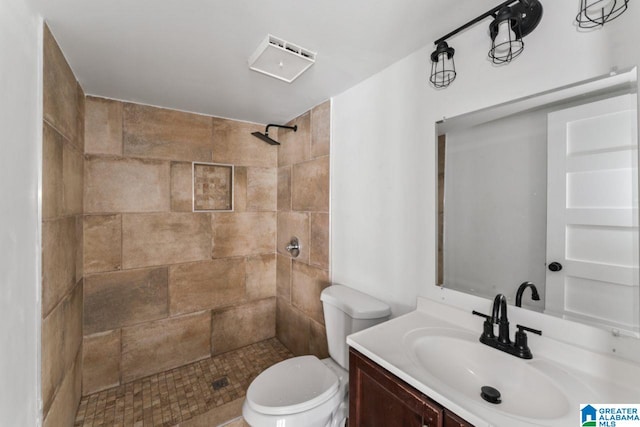 bathroom with vanity, a tile shower, and toilet