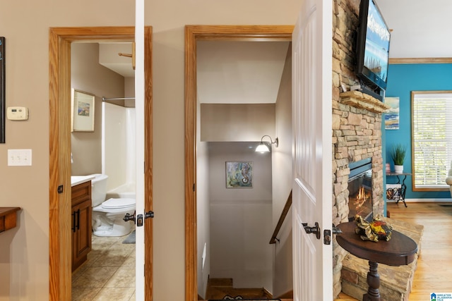 bathroom with walk in shower, toilet, vanity, a fireplace, and tile patterned flooring