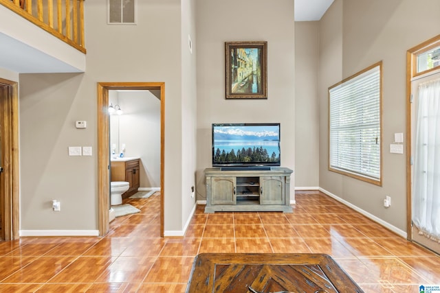 unfurnished living room featuring a towering ceiling and light tile patterned floors