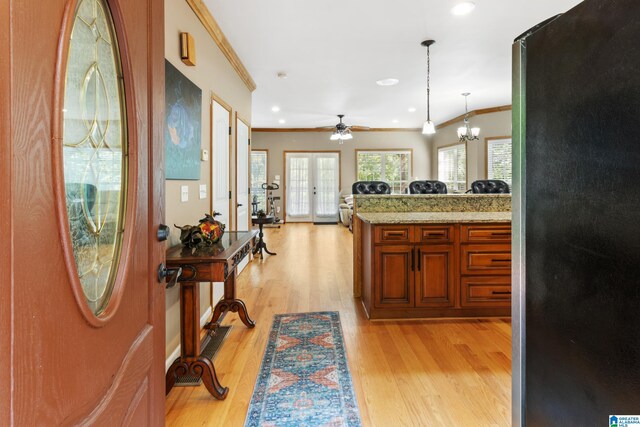 kitchen with ceiling fan with notable chandelier, fridge, hanging light fixtures, ornamental molding, and light hardwood / wood-style flooring