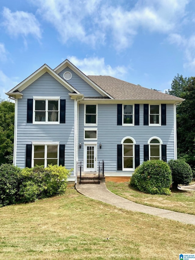 view of front of home with roof with shingles and a front lawn