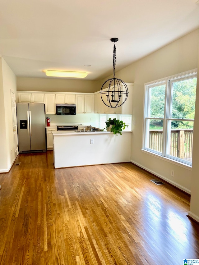 kitchen with electric range, pendant lighting, stainless steel fridge with ice dispenser, wood-type flooring, and white cabinets