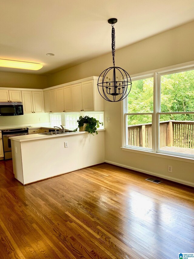 kitchen featuring electric stove, hanging light fixtures, a notable chandelier, white cabinetry, and light hardwood / wood-style flooring