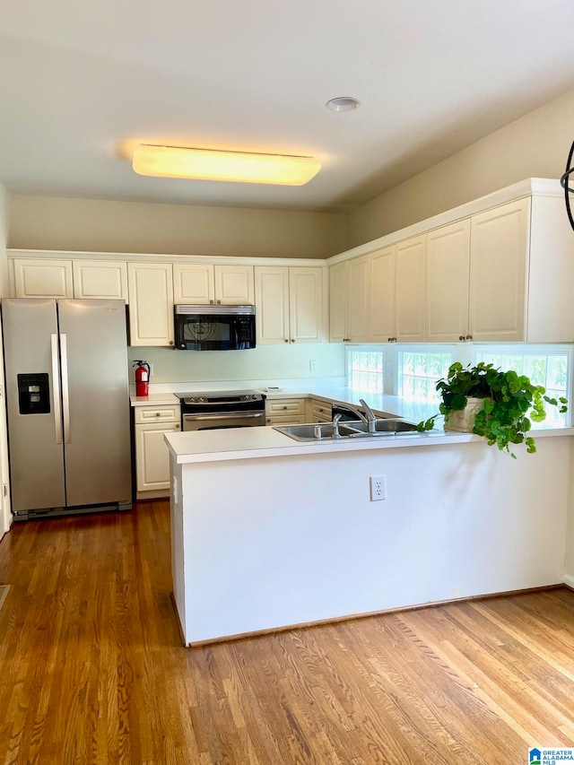 kitchen featuring sink, stainless steel appliances, hardwood / wood-style floors, and white cabinetry