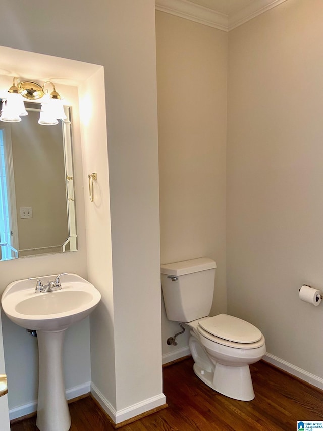 bathroom with crown molding, wood finished floors, toilet, and baseboards