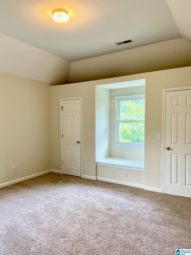 carpeted spare room featuring lofted ceiling