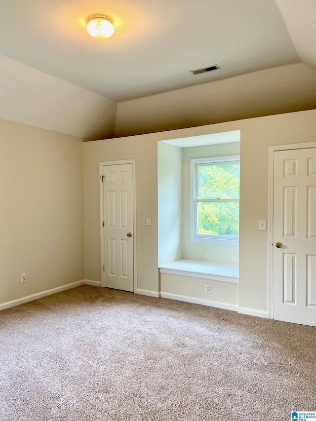 unfurnished room with lofted ceiling, carpet flooring, visible vents, and baseboards