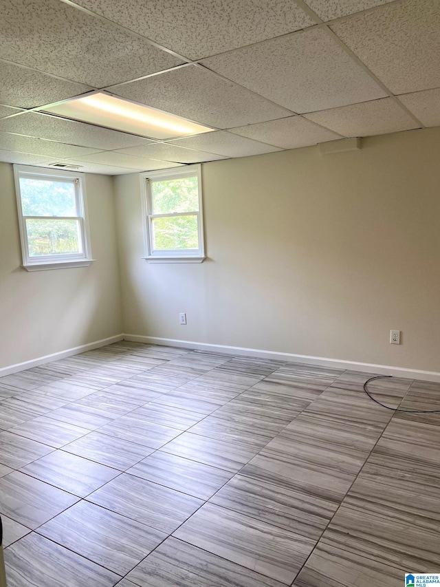 tiled empty room featuring a paneled ceiling