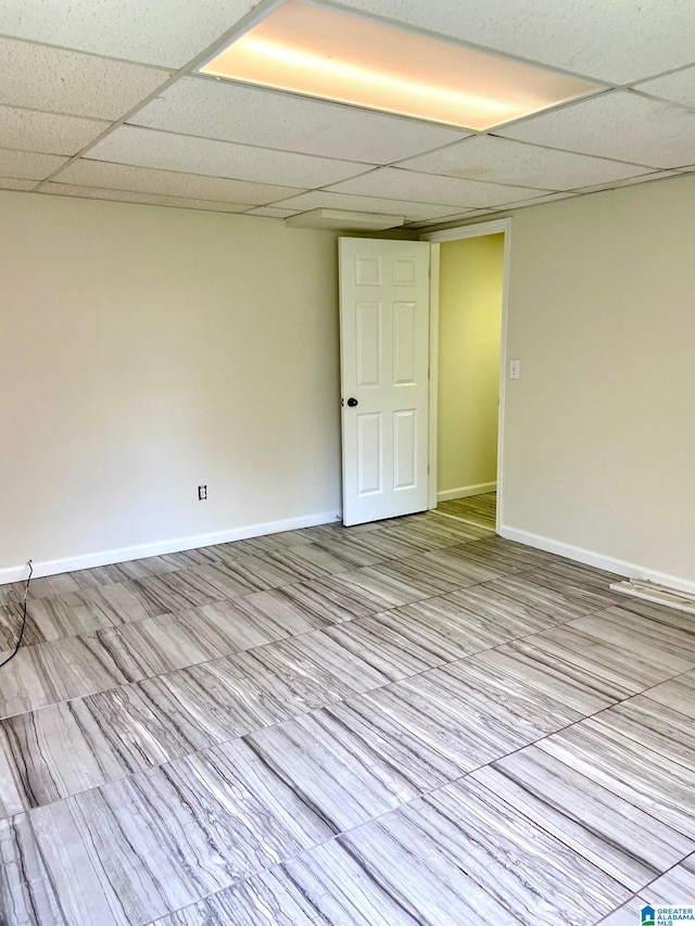 unfurnished room featuring a drop ceiling and baseboards