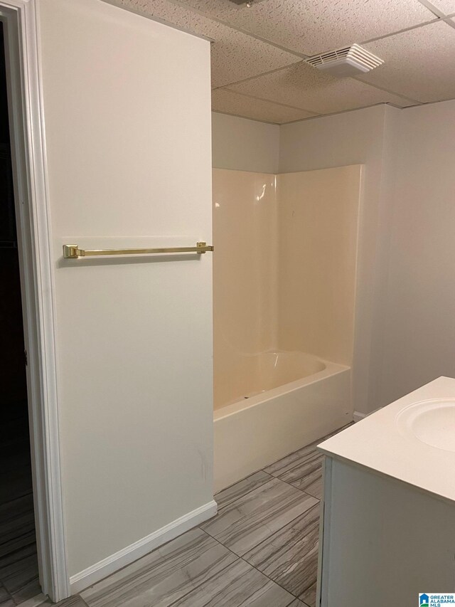 bathroom featuring tile patterned floors, vanity, a drop ceiling, and shower / washtub combination