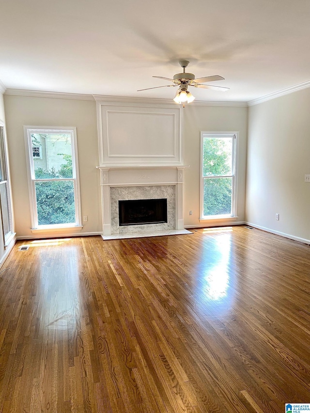 unfurnished living room featuring crown molding, a high end fireplace, ceiling fan, and hardwood / wood-style floors