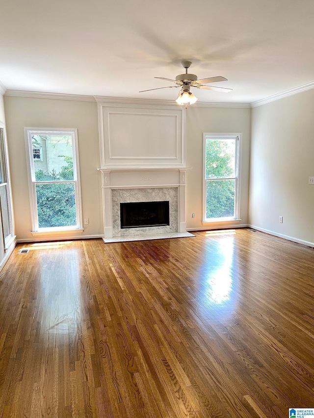 unfurnished living room with a premium fireplace, a ceiling fan, crown molding, and wood finished floors