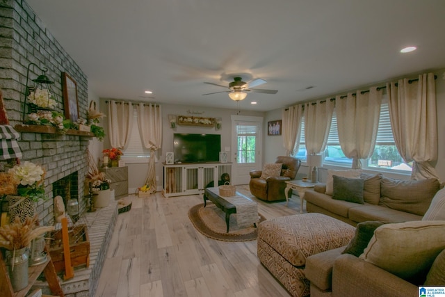 living room with ceiling fan, light hardwood / wood-style floors, and a brick fireplace