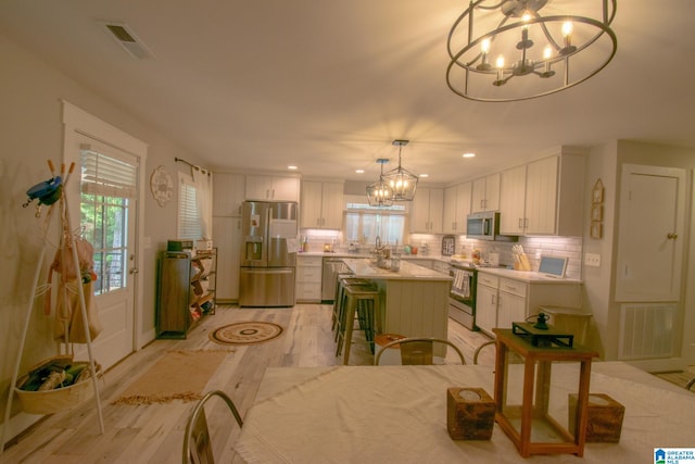 dining room featuring sink, light hardwood / wood-style flooring, and an inviting chandelier