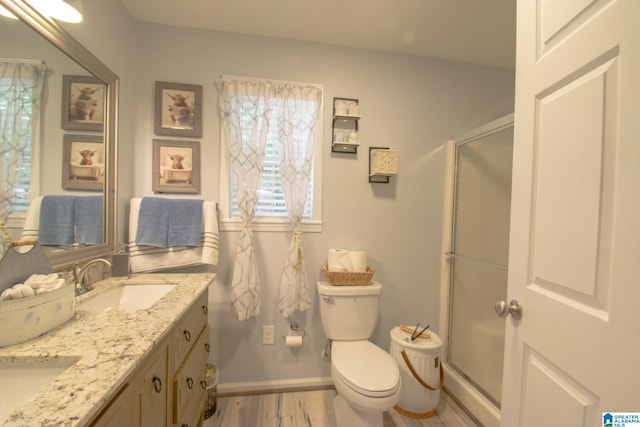 bathroom with an enclosed shower, double vanity, hardwood / wood-style floors, and toilet