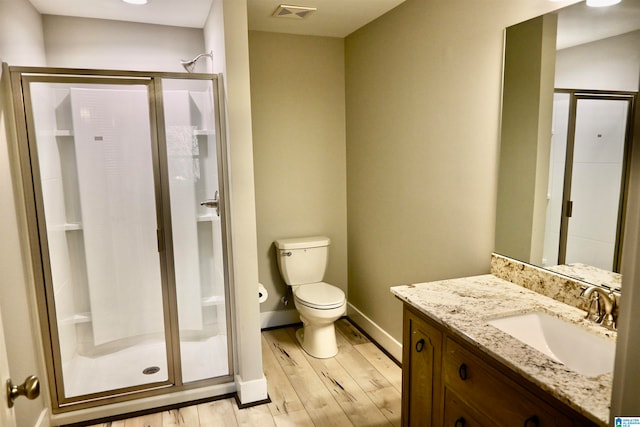 bathroom with hardwood / wood-style flooring, a shower with door, vanity, and toilet