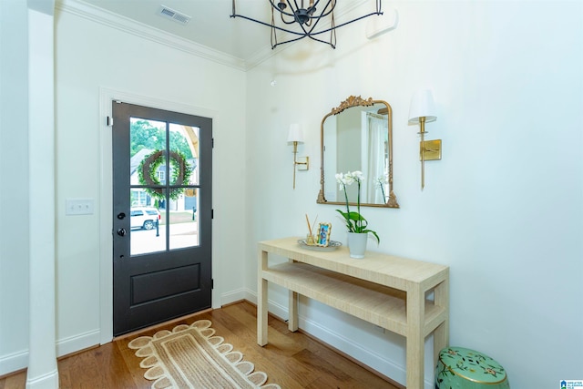 entrance foyer featuring an inviting chandelier, ornamental molding, and hardwood / wood-style floors