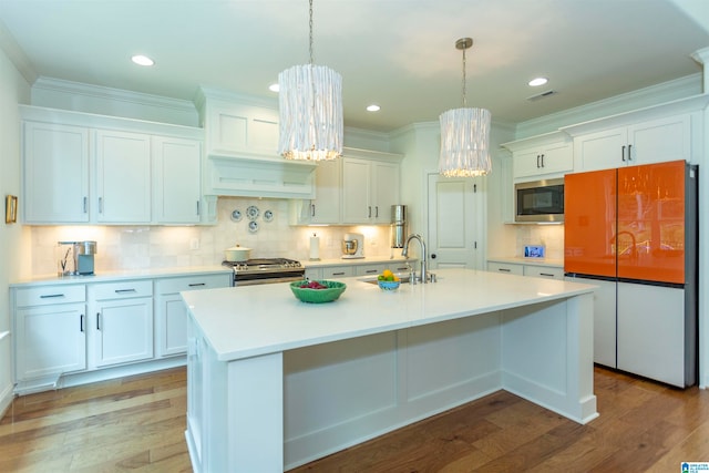 kitchen featuring stainless steel appliances, hardwood / wood-style floors, an island with sink, sink, and white cabinetry