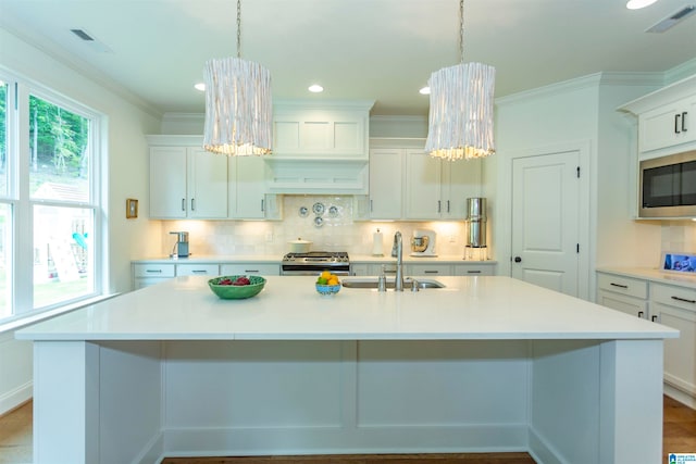 kitchen featuring sink, stainless steel appliances, a kitchen island with sink, and white cabinetry