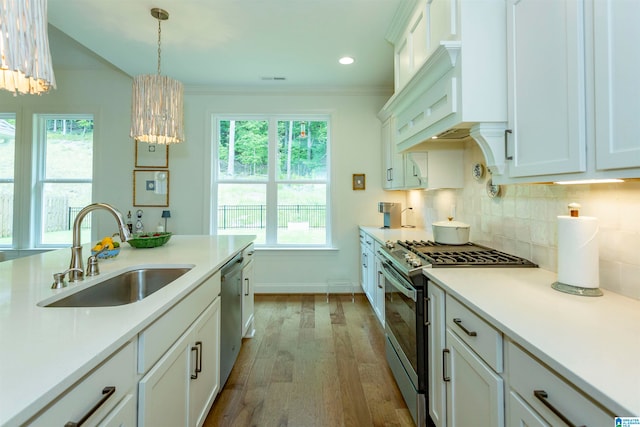 kitchen with pendant lighting, appliances with stainless steel finishes, hardwood / wood-style floors, sink, and backsplash