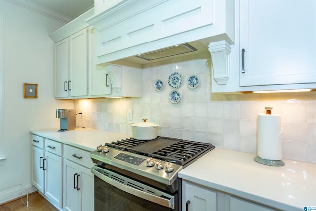 kitchen featuring custom exhaust hood, white cabinets, stainless steel gas range oven, backsplash, and ornamental molding