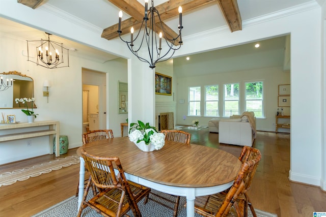 dining area featuring hardwood / wood-style flooring, a chandelier, beam ceiling, and ornamental molding