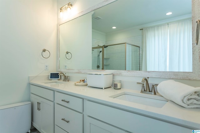 bathroom with crown molding, a shower with shower door, dual vanity, and toilet