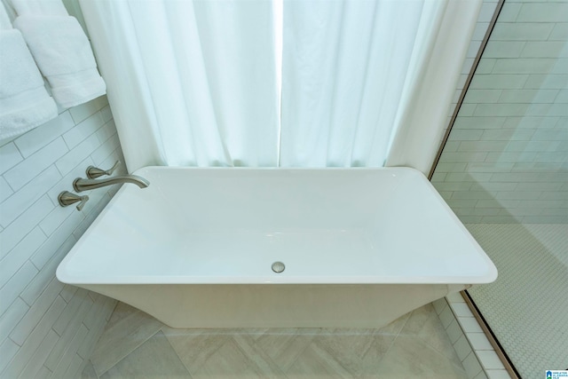 bathroom featuring tile walls, tile patterned floors, and a bathing tub