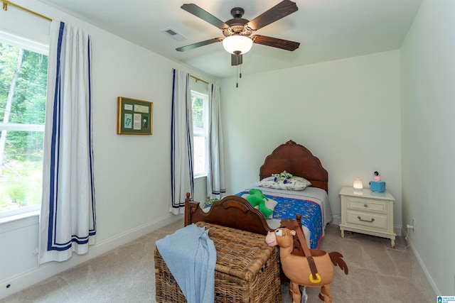 bedroom featuring ceiling fan, multiple windows, and light carpet