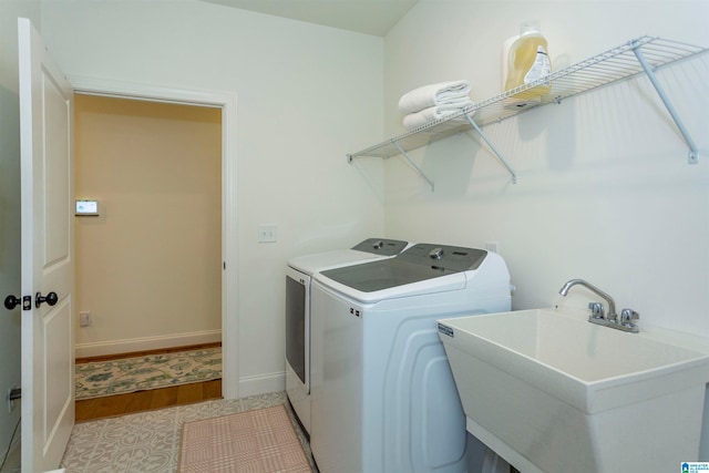 clothes washing area with independent washer and dryer, sink, and light hardwood / wood-style floors