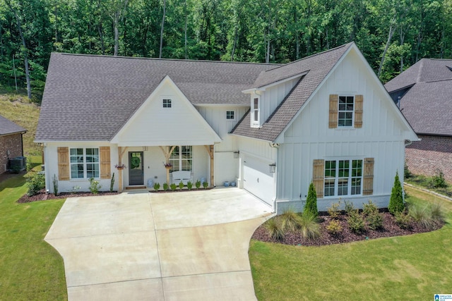 view of front of property featuring a garage, cooling unit, and a front lawn