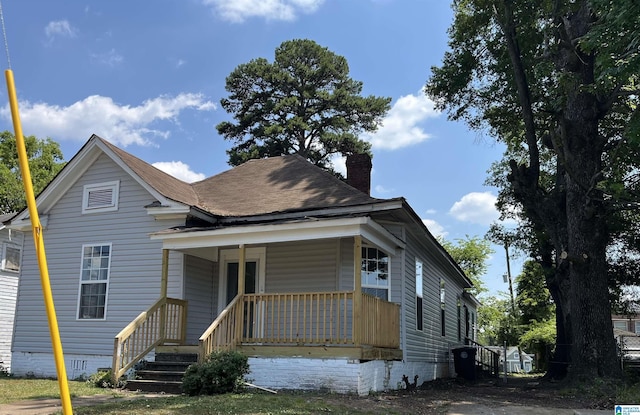view of front of house with a chimney, covered porch, and crawl space