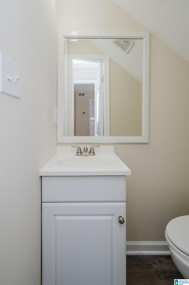 bathroom featuring vaulted ceiling, toilet, wood-type flooring, and vanity