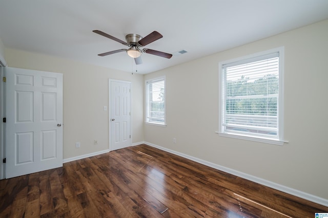 unfurnished bedroom with multiple windows, a closet, dark hardwood / wood-style floors, and ceiling fan